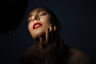 Siyah arka planda poz veren, gözleri kapalı genç bir kadının güzel portresi..