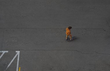 Genç bir adam kaykaya biniyor, en üst manzaralı, kaldırımda..