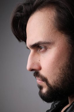 Düşünen sakallı genç adamın yan görünüş portresi. Dikey.