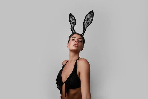 Retrato de mujer joven con orejas de conejo posando sobre fondo gris. —  Fotos de Stock