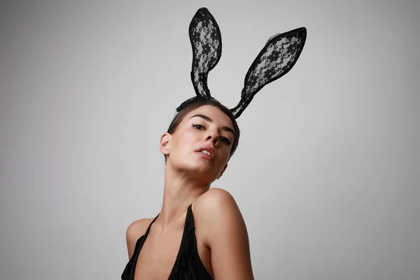 Gros plan portrait de jeune femme aux oreilles de lapin posant sur fond gris. — Photo