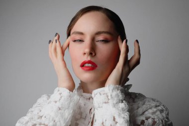 Kırmızı dudaklı ve yüzüne dokunan güzel genç bir manken. İzole edilmiş.