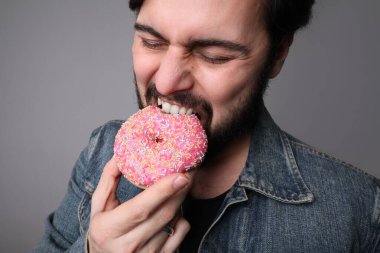 Pembe çöreği zevkle yiyen genç bir adamın kesilmiş portresi.. 