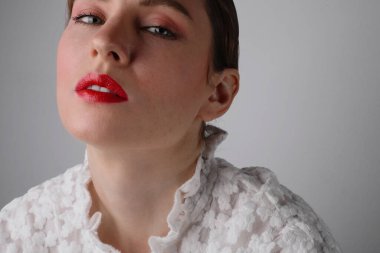 Kırmızı dudaklı, beyaz elbiseli güzel bir mankenin kesilmiş portresi. İzole edilmiş.