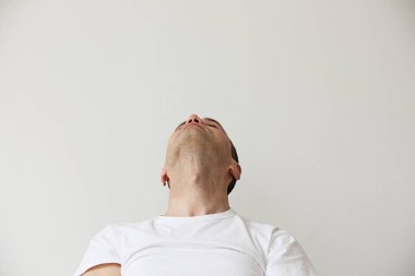 Beyaz duvarda poz veren beyaz bir adamın portresi.