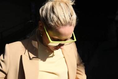 Bej takım elbiseli, dışarıda poz veren güzel bir kadın..