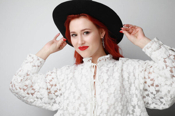 Charming young woman with red hair while standing on white background.