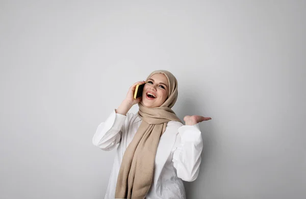 年轻快乐的穆斯林女子通过电话说话的画像。被隔离在白墙上. — 图库照片