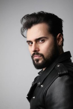 Stüdyoda poz veren yakışıklı sakallı genç adamın dikey portresi..