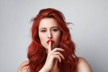 Kızıl saçlı genç bir kadın gri arka planda 