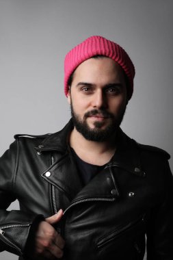 Pembe şapkalı, yakışıklı, sakallı bir adamın dikey resmi..