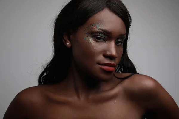 Headshot de mulher negra posando no estúdio, com maquiagem brilhante. — Fotografia de Stock