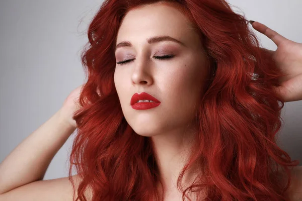 Close-up de bela jovem mulher com cabelo vermelho posando sobre fundo cinza. — Fotografia de Stock