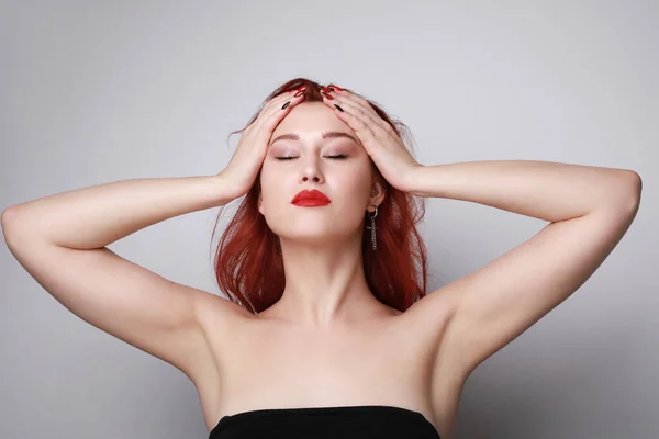 Close-up de mulher bonita com cabelo vermelho e olhos fechados posando sobre a parede cinza. — Fotografia de Stock