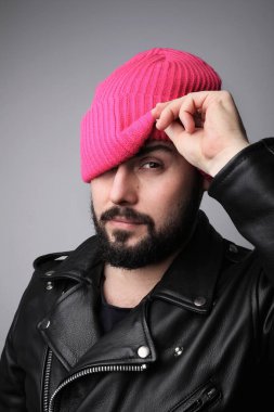 Kameraya bakan pembe şapkalı yakışıklı sakallı adamın dikey portresi.