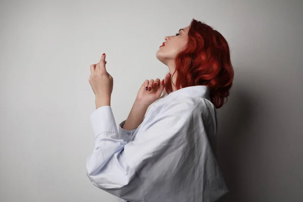 Mujer joven con el pelo rojo posando en el estudio sobre fondo gris. Aislado. —  Fotos de Stock