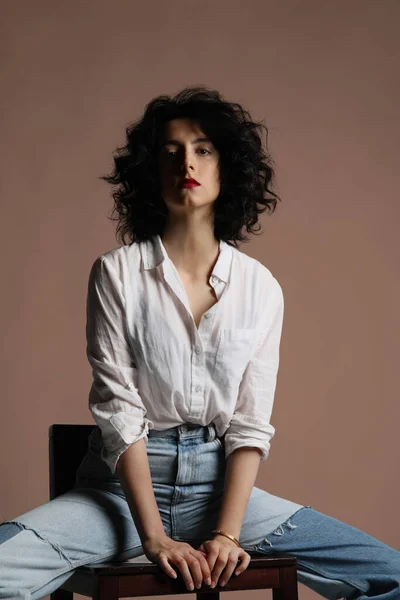 Retrato vertical de mujer joven lleva camisa blanca posando sobre pared beige. — Foto de Stock