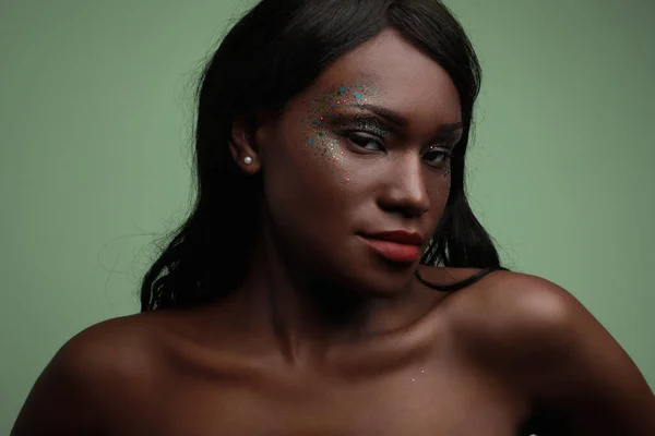 Close-up da jovem mulher negra posando no estúdio, com maquiagem brilhante. — Fotografia de Stock