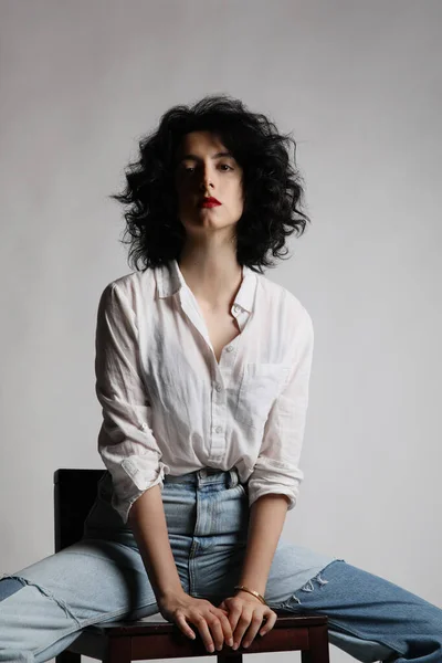 Retrato de mujer joven lleva camisa blanca posando sobre pared blanca. Vertical. — Foto de Stock