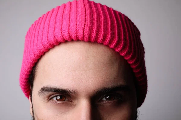 Vágott portré komoly fiatalember visel kötött rózsaszín kalap át fehér fal. — Stock Fotó