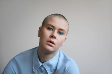 Beyaz duvarın üzerinde poz veren güzel kel bir kadının stüdyo portresi. İzole edilmiş.