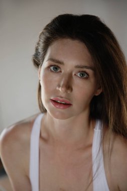 Beyaz kadının dikey yakın plan portresi, doğrudan kameraya bakıyor..