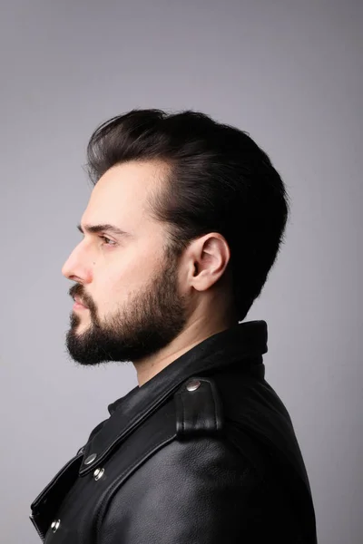 Handsome serious young man wear leather jacket over white wall. Vertical. — Stock Photo, Image