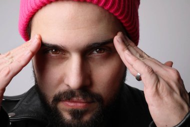 Ciddi genç erkek model portresi beyaz duvarın üzerine deri ceket giyer. Kırpılmış.