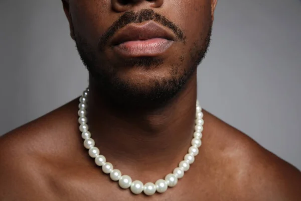 Close-up de homem negro sem camisa com colar de pérolas sobre fundo cinza. — Fotografia de Stock