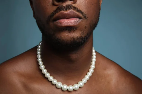 Retrato recortado de homem negro sem camisa com colar de pérolas sobre a parede azul. — Fotografia de Stock