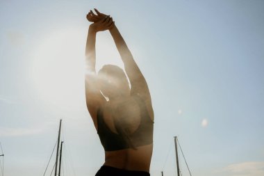 Esneme hareketleri yapan genç bir kadının arka görüntüsü. Açık hava..