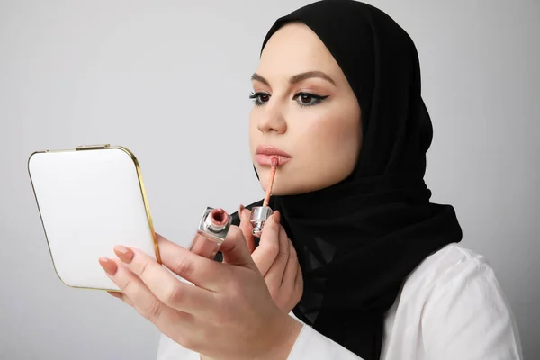 Крупный план арабской девушки, делающей макияж, изолированной на белой стене. — стоковое фото