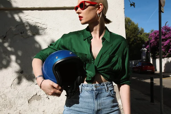 야외에서 오토바이 헬멧을 들고 거리를 바라보는 젊은 여자 — 스톡 사진