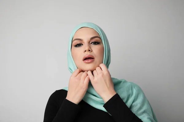 Jovem mulher árabe corrigindo seu hijab, isolado sobre a parede branca. — Fotografia de Stock