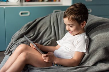 Kendini izole etme modu ve uzaktan öğrenme. Çocuk bir sandalyeye oturur ve tablette öğrenir, çocuk tatmin olur. Evde eğitim, Sosyal Mesafe, E-öğrenim çevrimiçi eğitim.