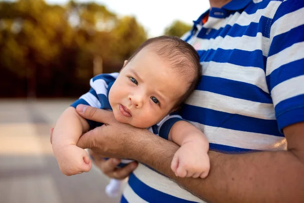Father holds in his arms a baby. Both are dressed in bright blue striped T-shirts. A family. Father's day. Father and son.