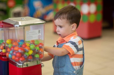 Küçük sarışın çocuk markette oyun oynuyor.