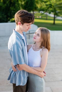 Parkta el ele tutuşup sarılan iki genç. İlk aşk.