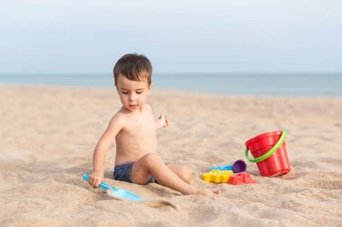 Sevimli çocuk kumsalda oyuncaklarla oynuyor. Yaz tatili