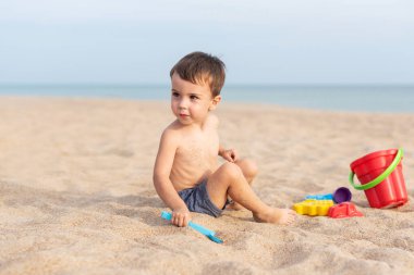 Sevimli çocuk kumsalda oyuncaklarla oynuyor. Yaz tatili