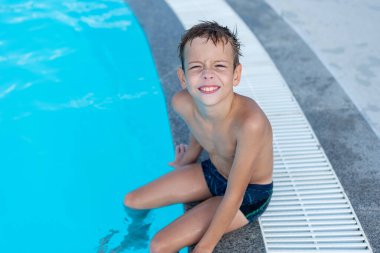 Havuzun kenarındaki çocuk gülümsüyor. Açık hava yüzme havuzu.