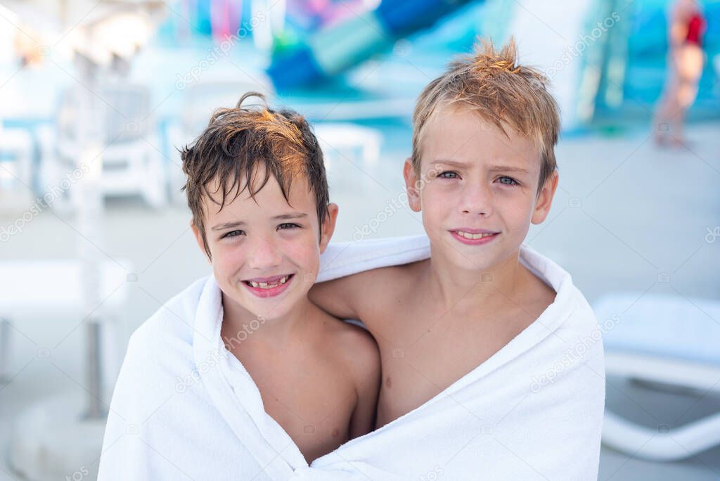 Two boys wrapped in a bath towel after swimming in the outdoor pool.