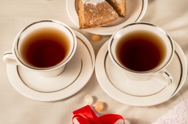 İki beyaz bardak elmalı turta ile. Kırmızı kurdele