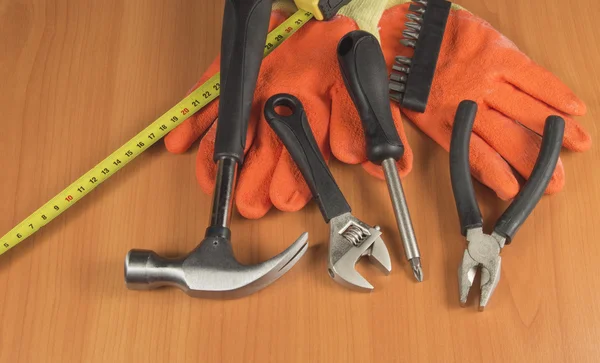 Arbejdshandsker og forskellige værktøjer på træ baggrund - Stock-foto
