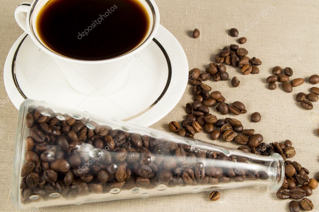 Cup and coffee grains in a glass jar on  linen napkin
