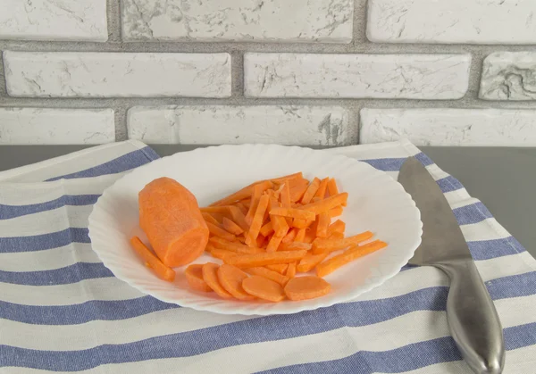 Нарезанная свежая морковь на белой тарелке и ноже. Здоровое питание — стоковое фото