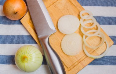 Soğan, dilimlenmiş bıçakla, ahşap kesme tahtası üzerinde peçete çizgili