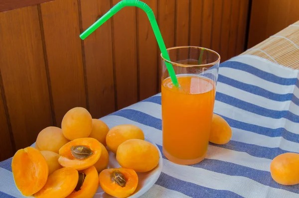 Suco de damasco em um copo com palha e frutas em guardanapo — Fotografia de Stock