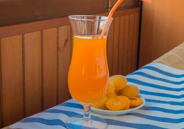 Абрикосовый сок в стакане с соломой и свежими фруктами на салфетке — стоковое фото