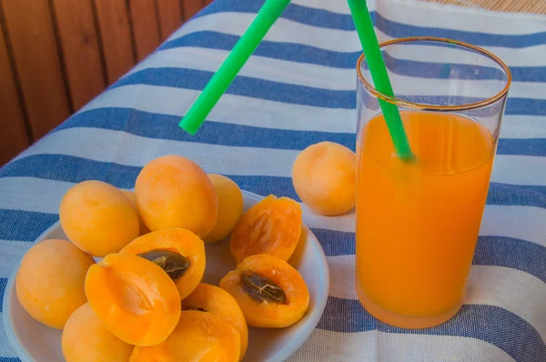 Абрикосовый сок в стакане с соломой и фруктами на салфетке — стоковое фото